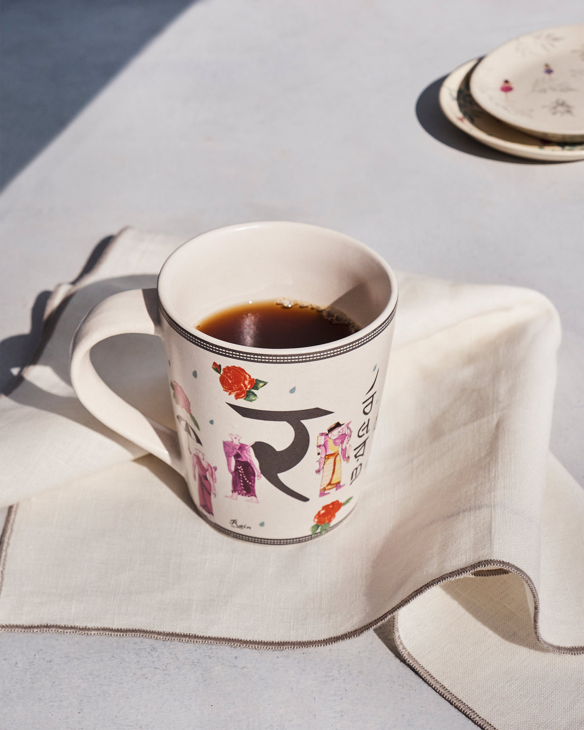 Ravenala mug with Devanagari letter filled with tea on a napkin.