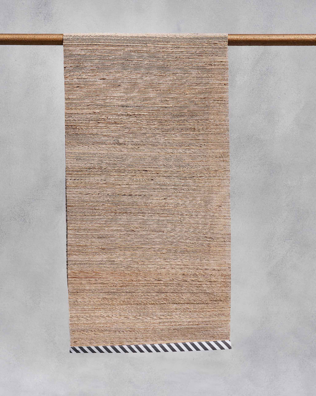 Natural banana fibre runner with a black-and-white diagonal striped border.