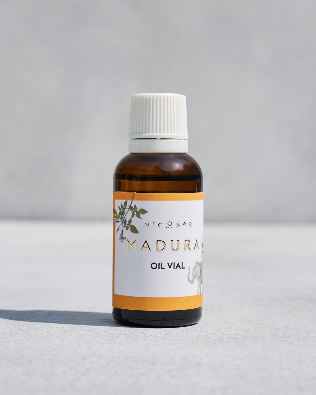 Madurai Vial amber glass bottle with a white cap and orange label.