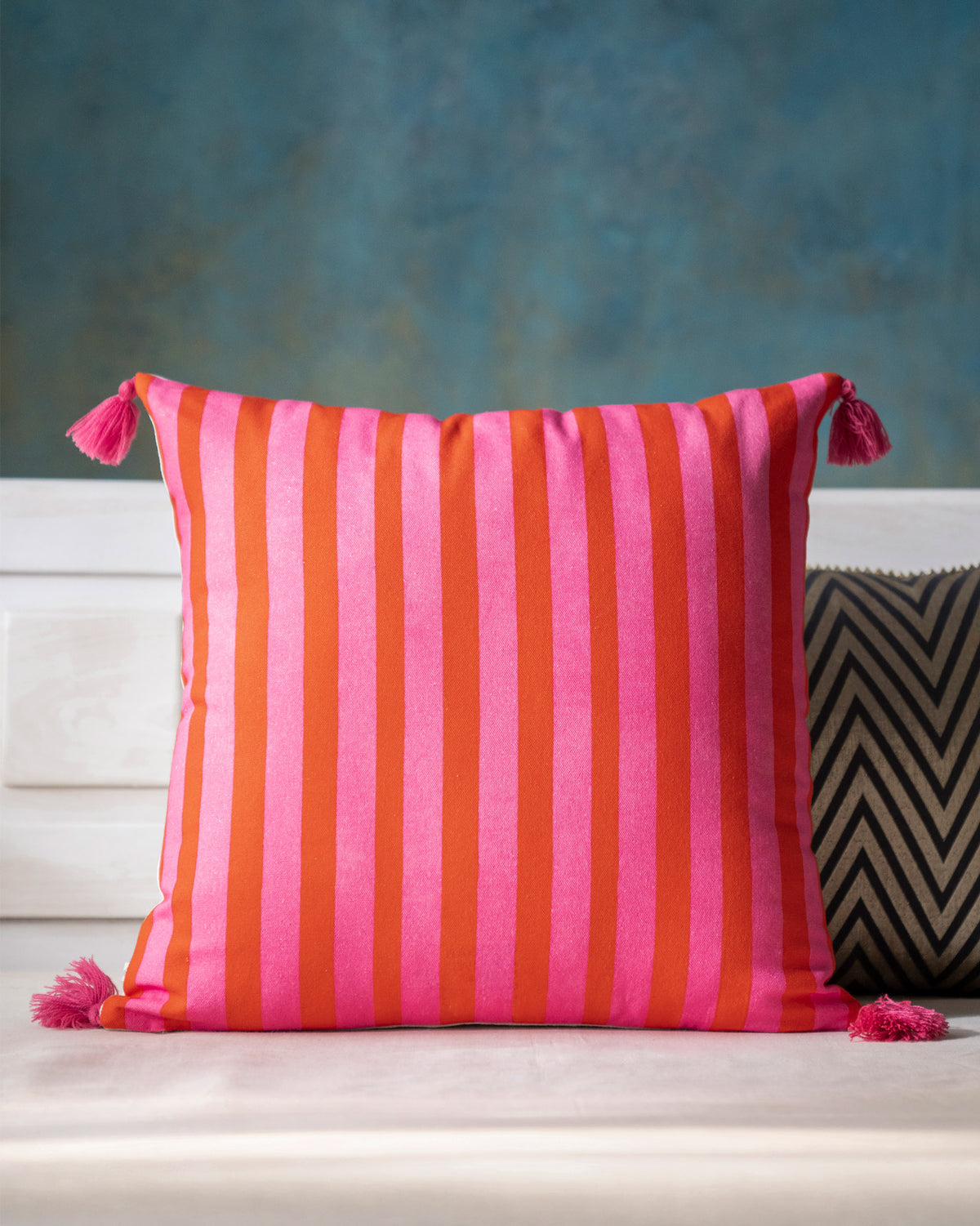 Back of Nirvana cushion cover in pink and orange stripes, with tassels.