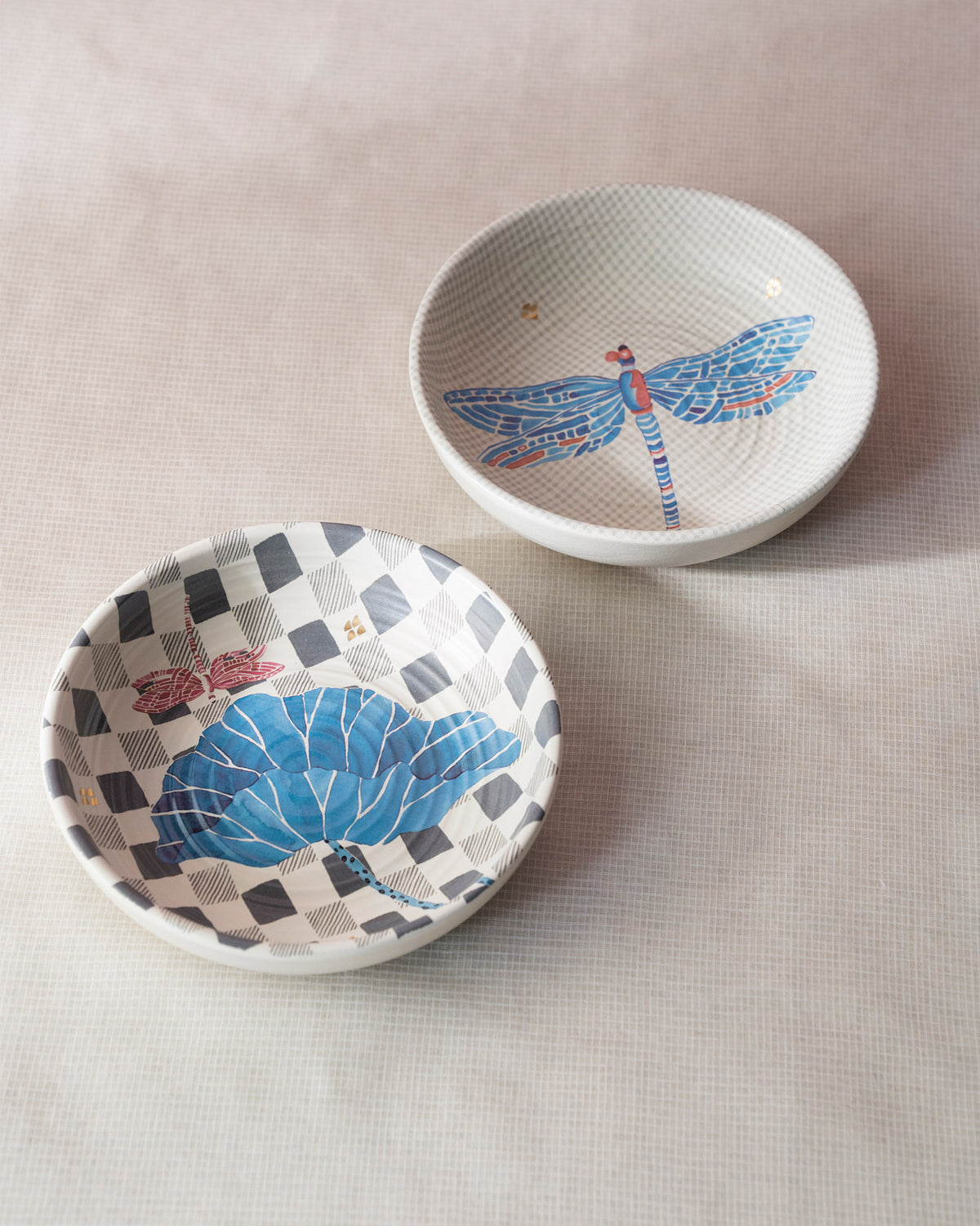 Stacked Nectar shallow bowls showing blue dragonfly and lotus leaf interior prints.