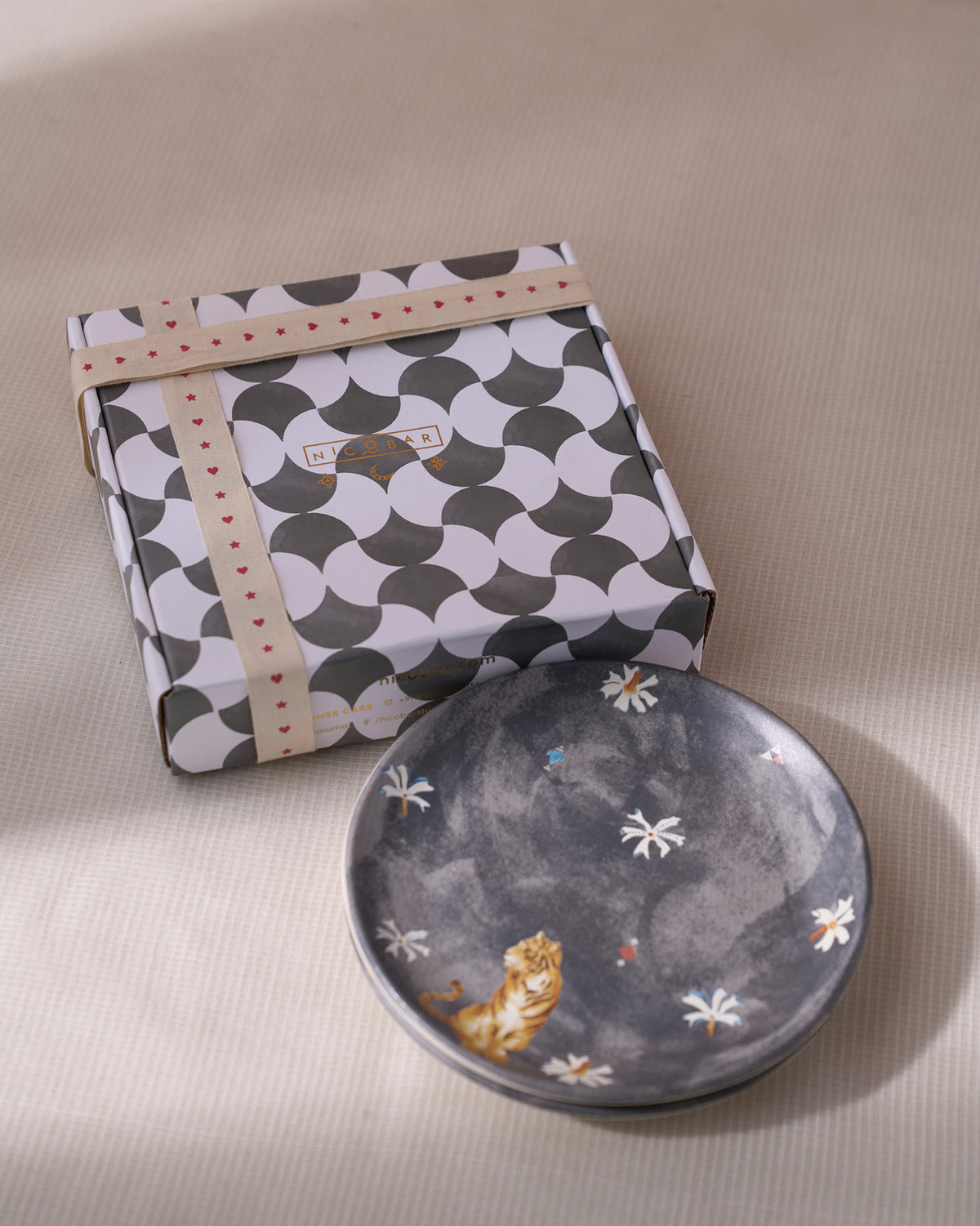 Charcoal Nadi quarter plate with tiger print in front of its Nicobar gift box.