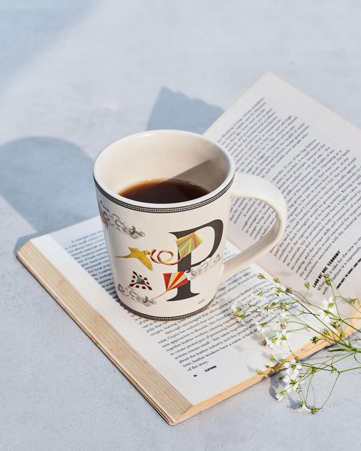 Cream Patang mug with a black letter P and colorful kite illustrations.
