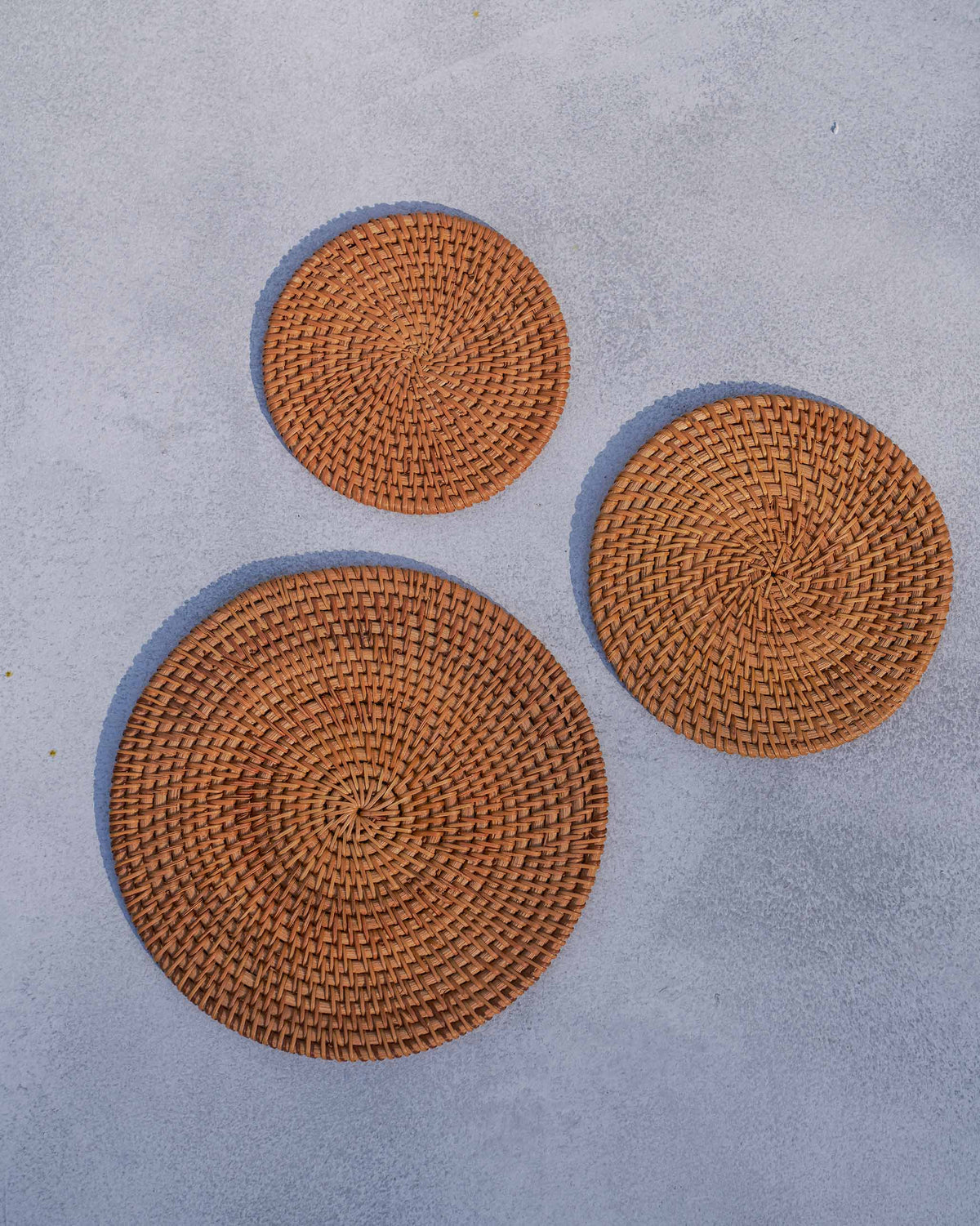 Overhead view of three round Rattan Trivets in woven rattan.