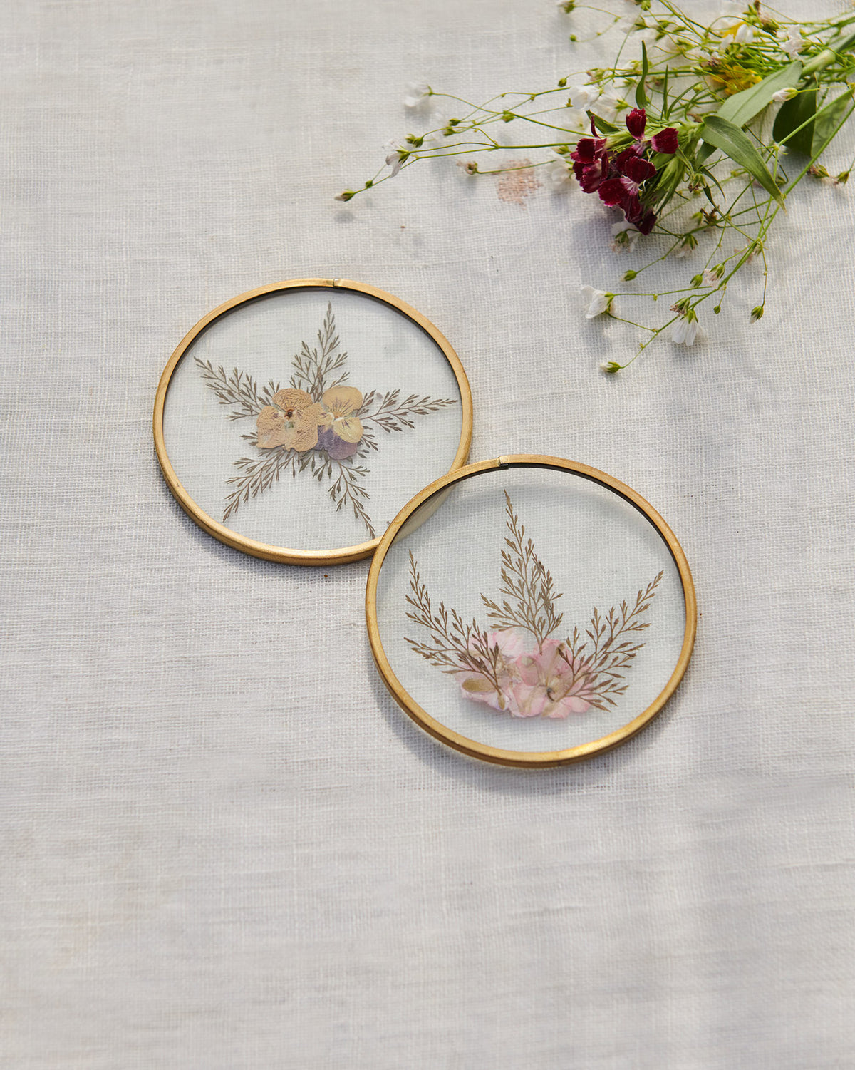 Set of two Waadi Coasters with pressed flowers and gold rims.