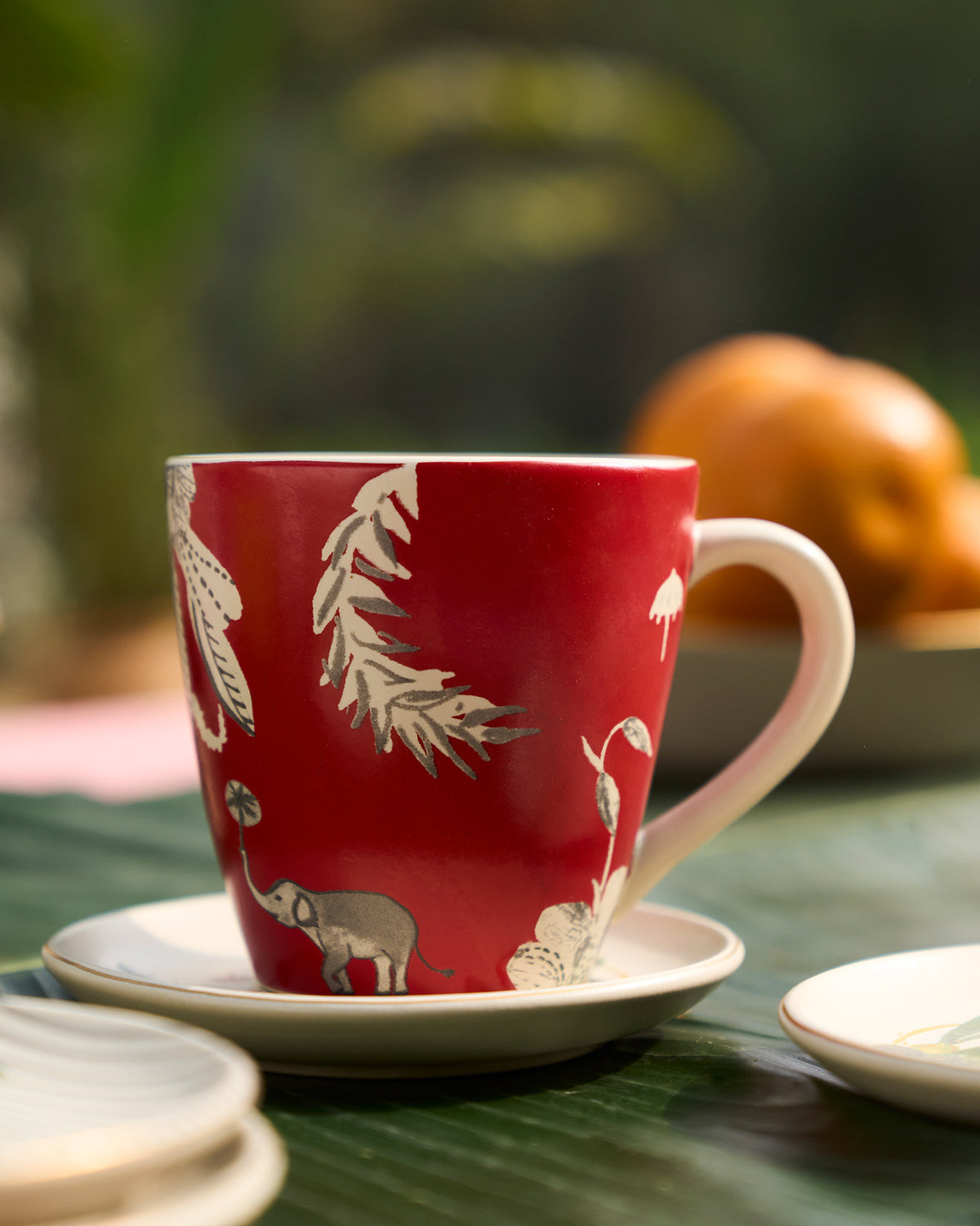 Red Thazin conical mug with white leaf and elephant motifs, shown at a three-quarter angle.