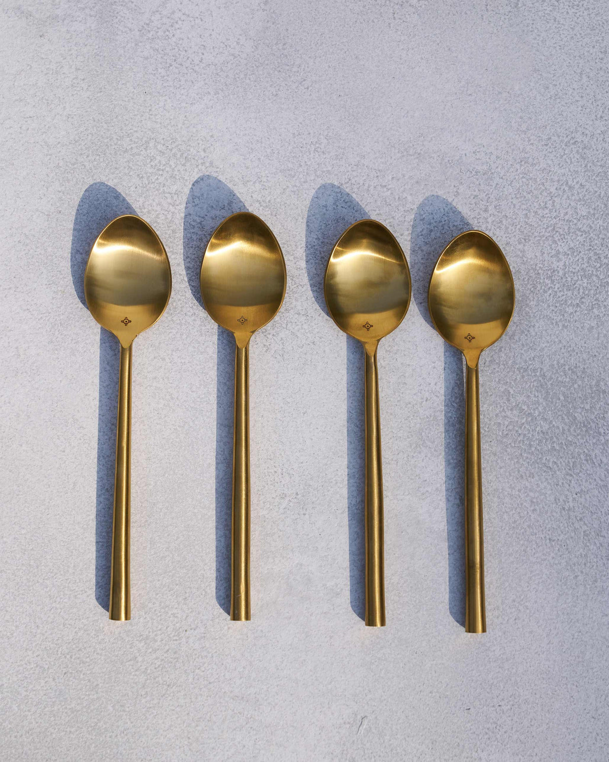 Set of four matte gold Sitara spoons laid in a neat row.