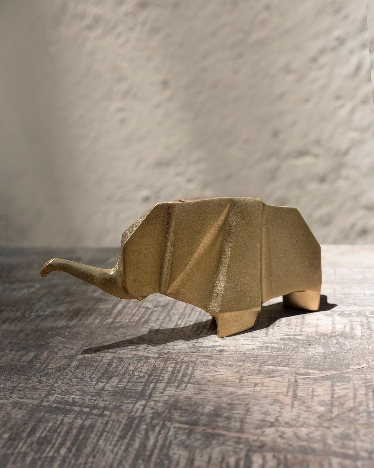 Side view of a gold Elephant origami showing its folded panels.