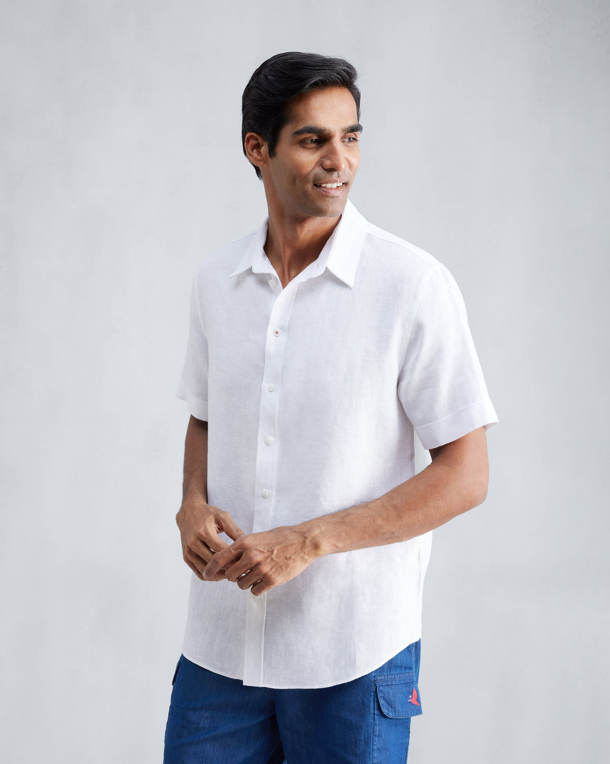 Person wearing a white half-sleeve shirt over blue shorts.