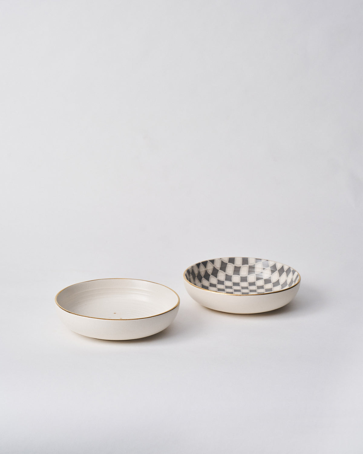 Pair of Fez Shallow Bowls with cream and checkered interiors and gold rims.