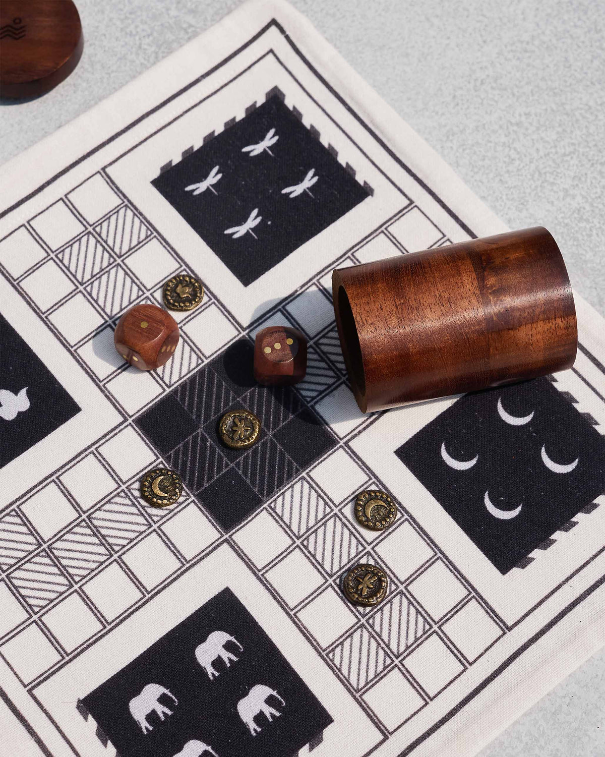 Close-up of Nico Ludo brass tokens and wooden dice on the cloth board.