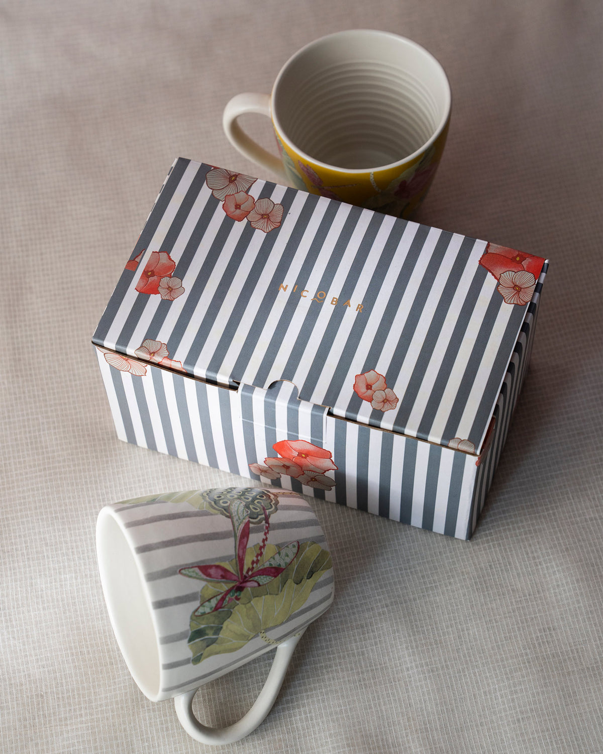 Pair of Lotus Garden mugs beside a striped Nicobar gift box.