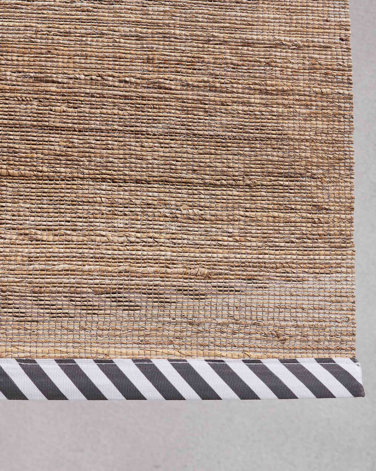 Close-up of banana fibre weave meeting a black-and-white striped border.