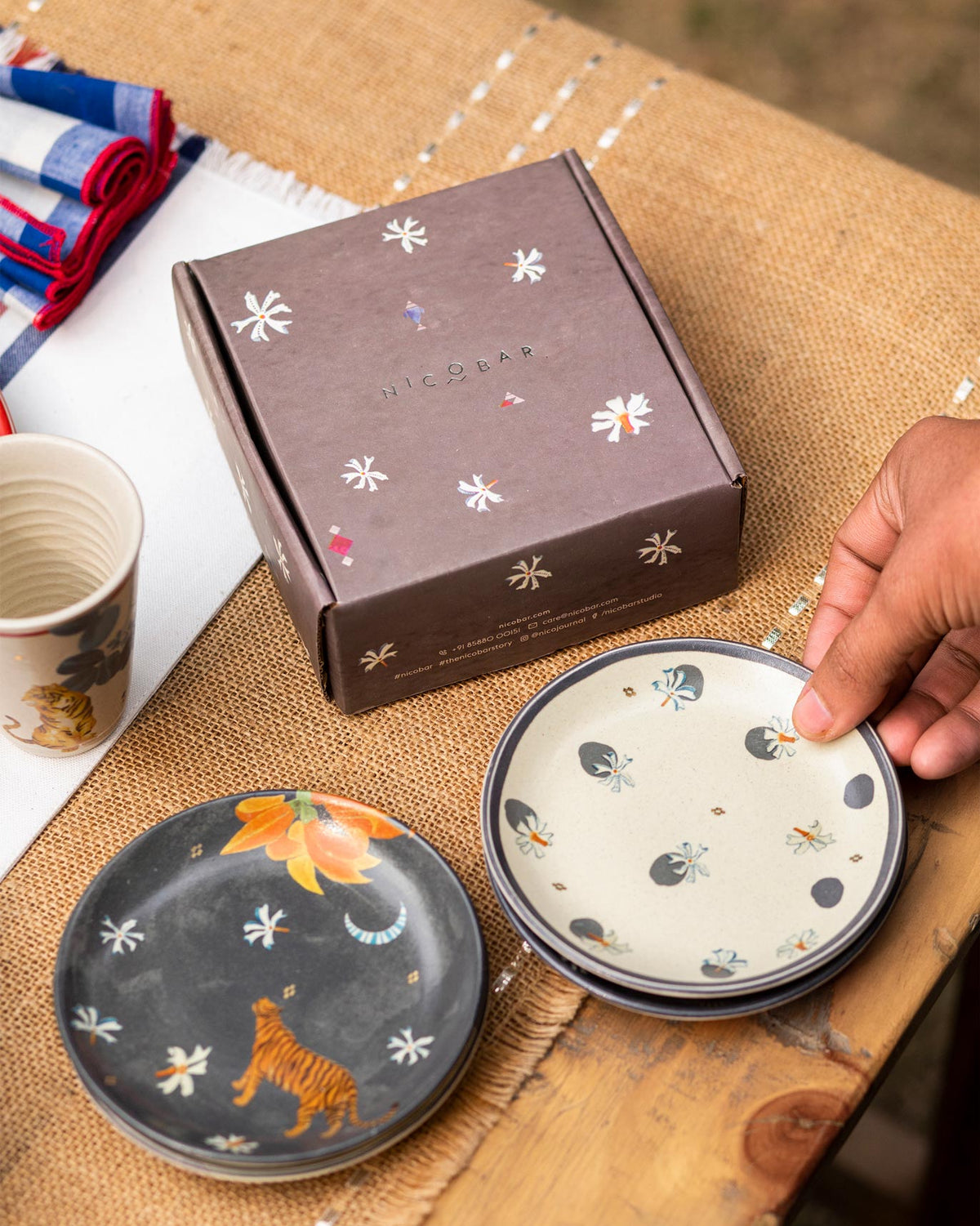 Nadi tea plate with a tiger motif beside a brown gift box.
