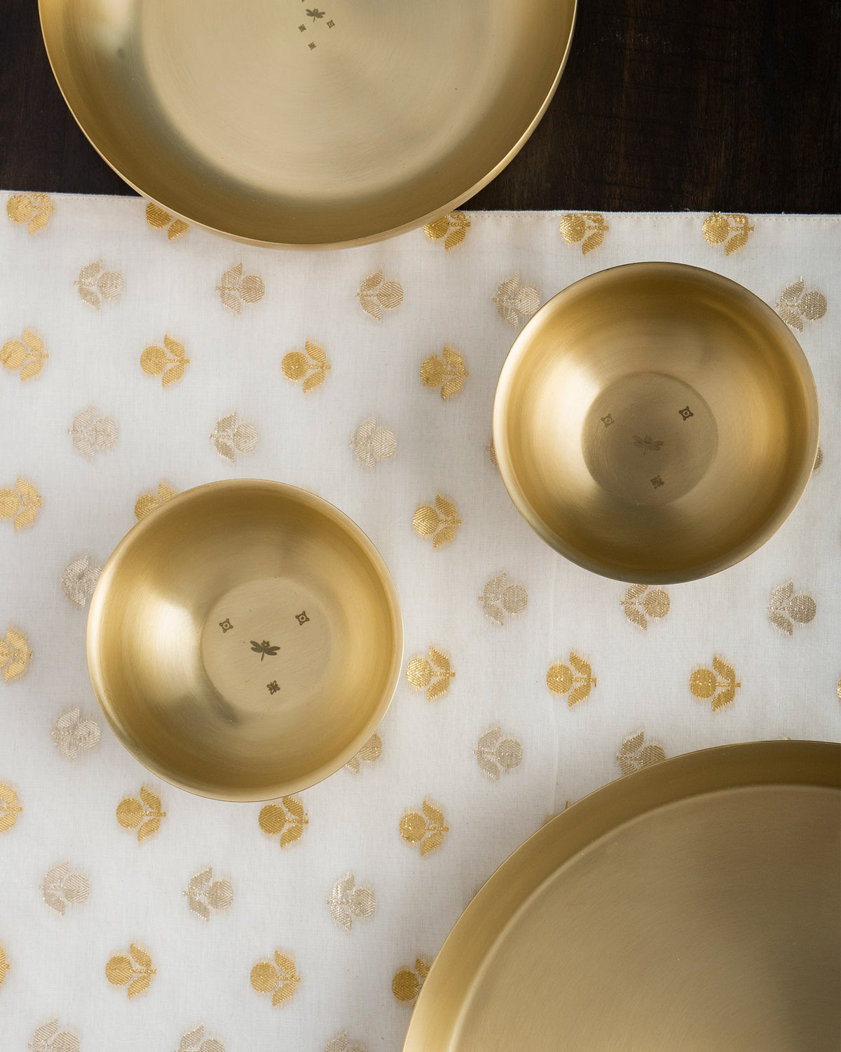 Madhu brass dessert bowls with dragonfly etch beside matching plates.
