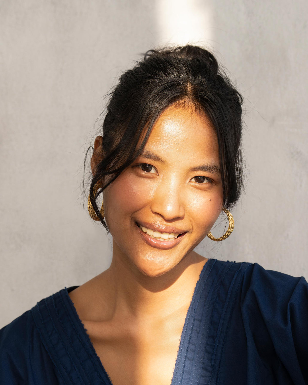 Person wearing gold Sea Shore Hoops with a braided texture.