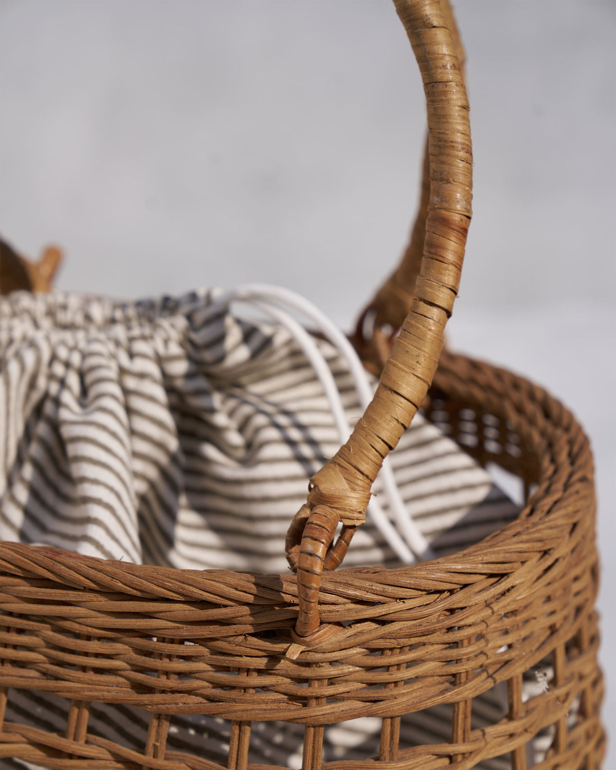 Close-up of Khasi Lunch Basket showing its woven body, handle and striped pouch.