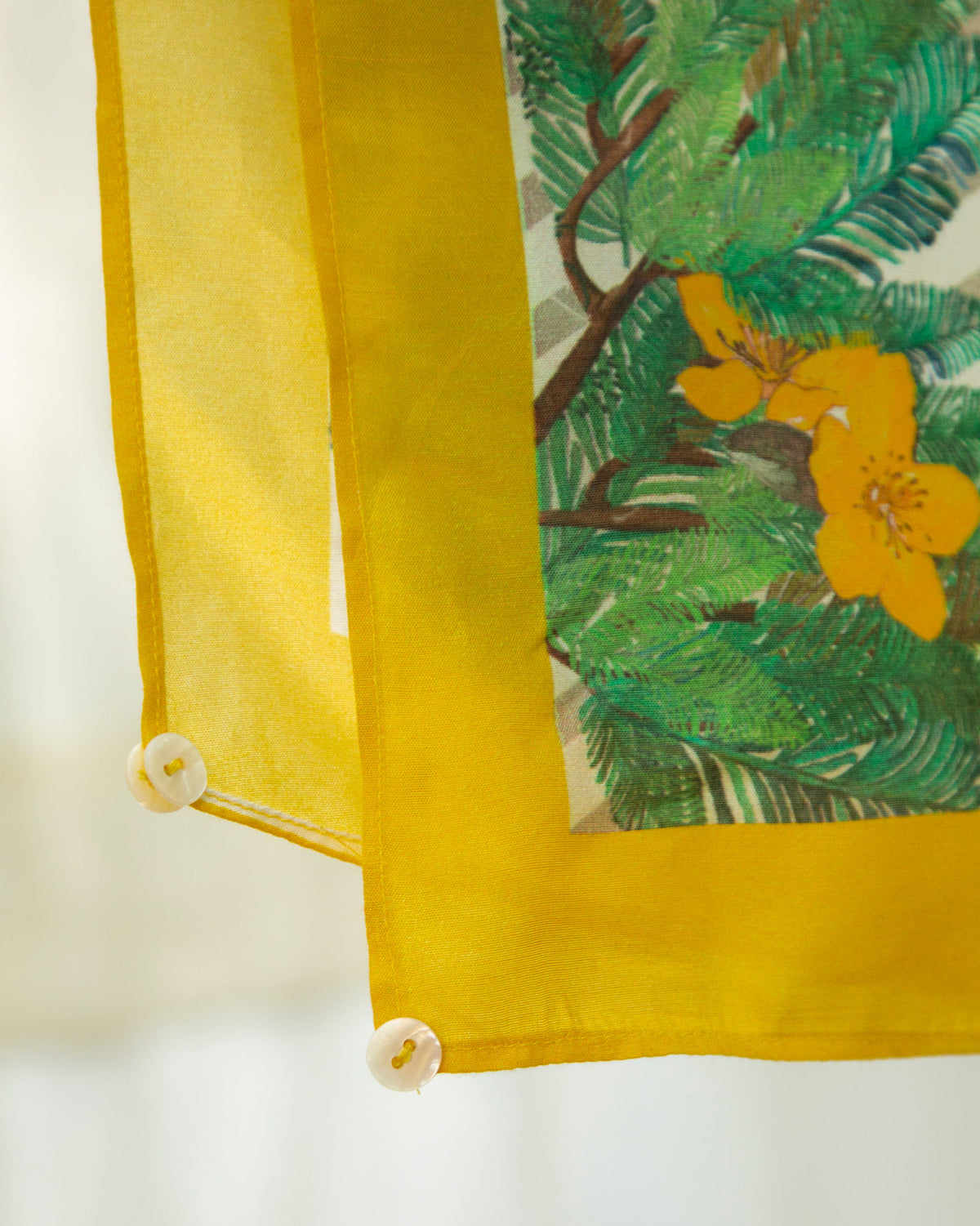 Close-up of the Foliage Sarong corner showing yellow flowers and cream buttons.
