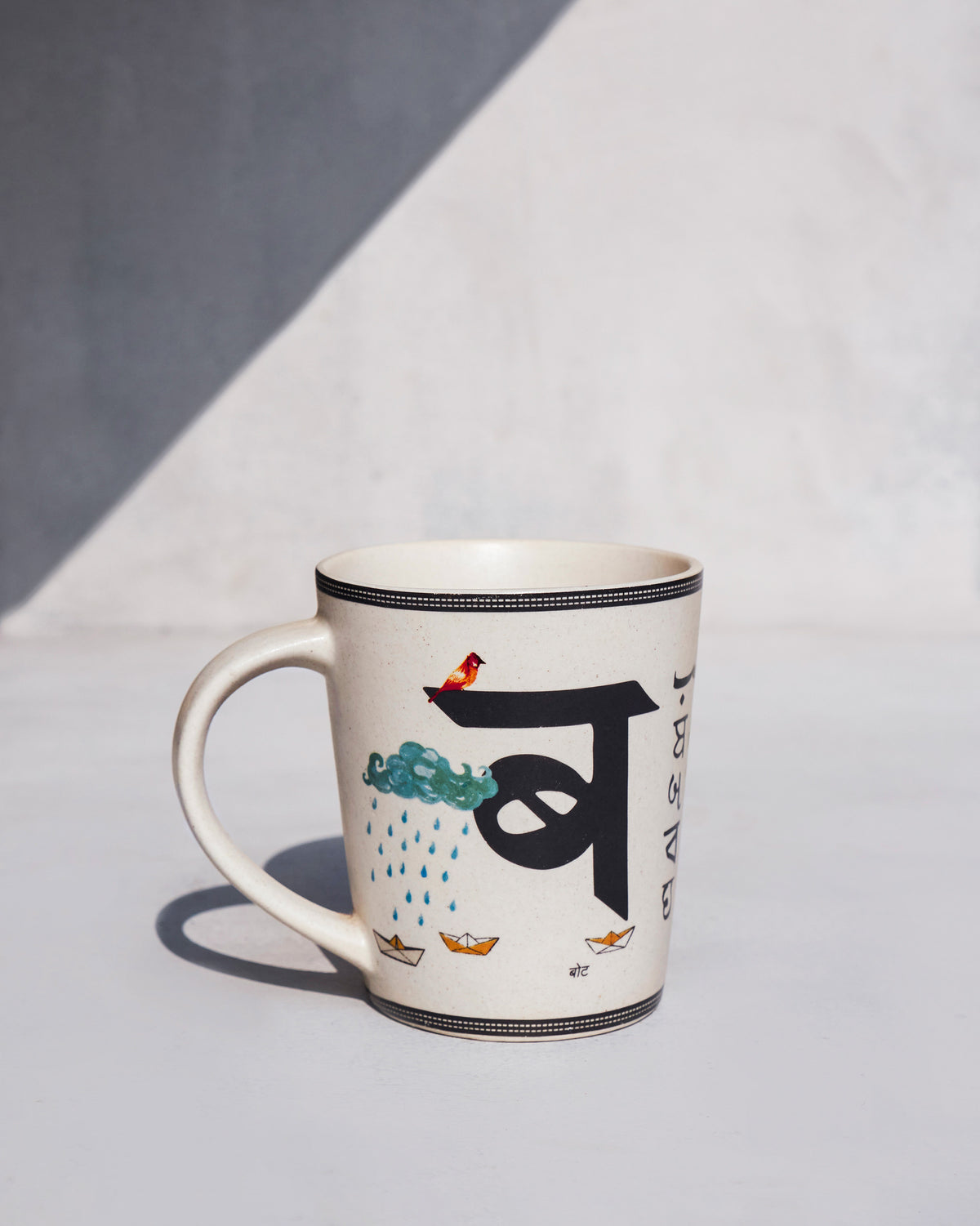 Cream Badal mug with Devanagari ब, cloud, and rain motifs.
