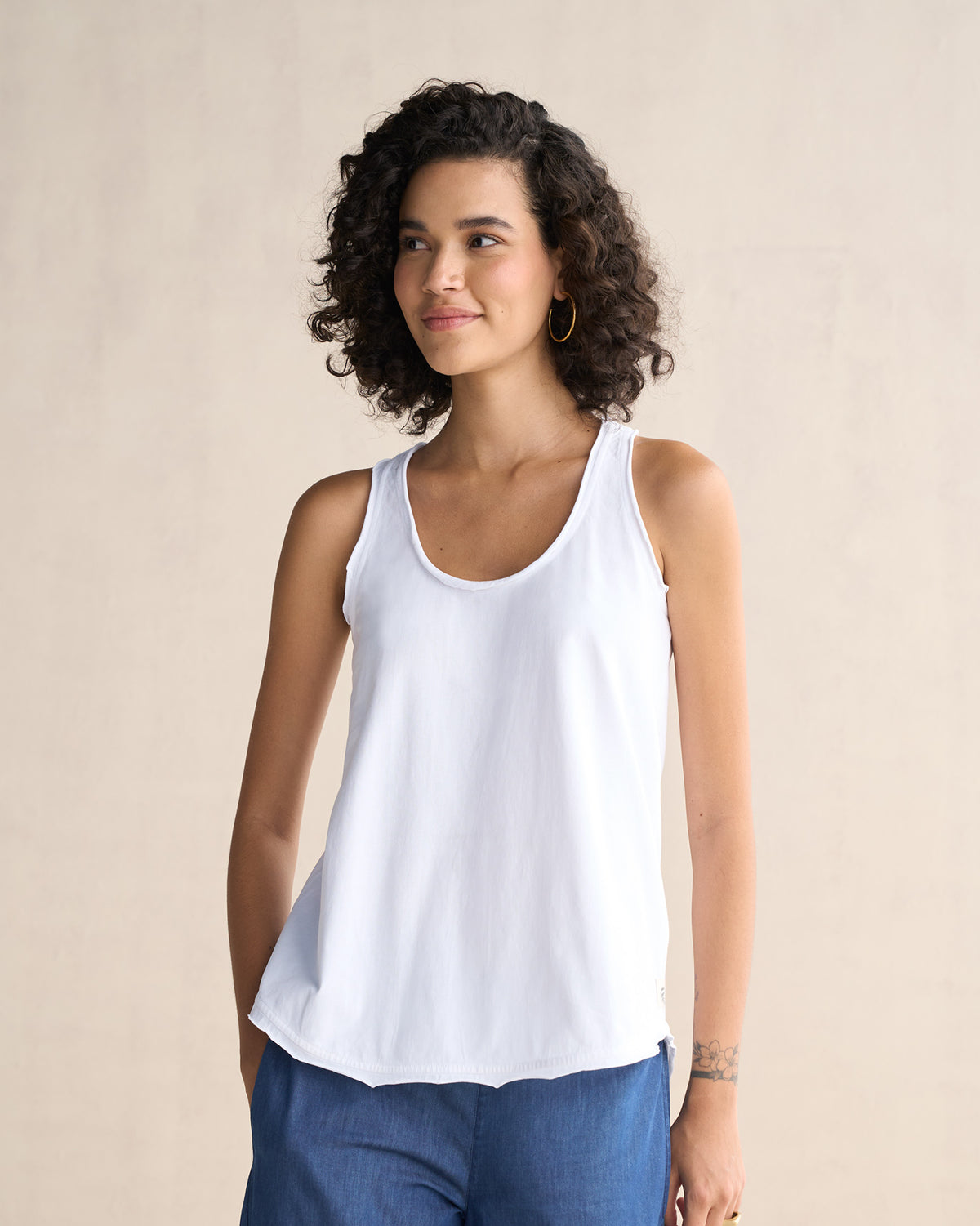 Side view of a white Ukiyo racerback tank showing the curved hem.