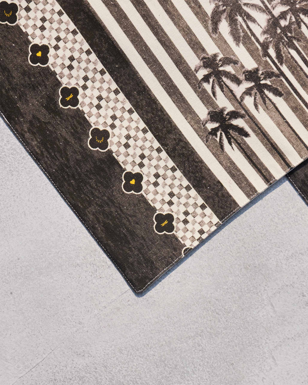 Close-up of a Midnight placemat corner showing the checked border and palm trees.