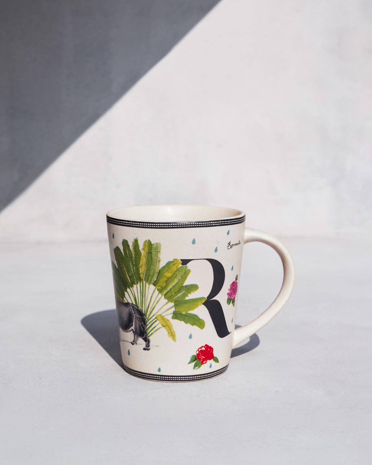 Ivory Ravenala mug with letter R, traveller palm and rose motifs.