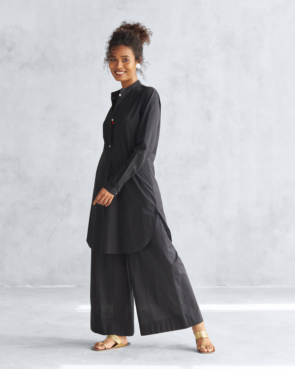 Three-quarter view of a black mid-length kurta with a curved hem.