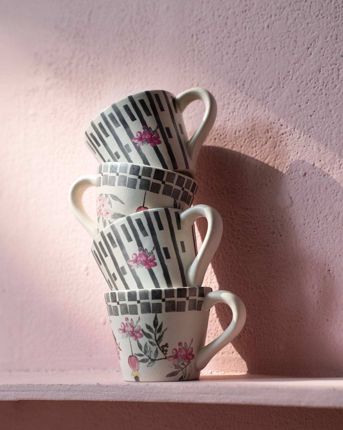Stack of four Nectar espresso mugs alternating floral and striped botanical prints.