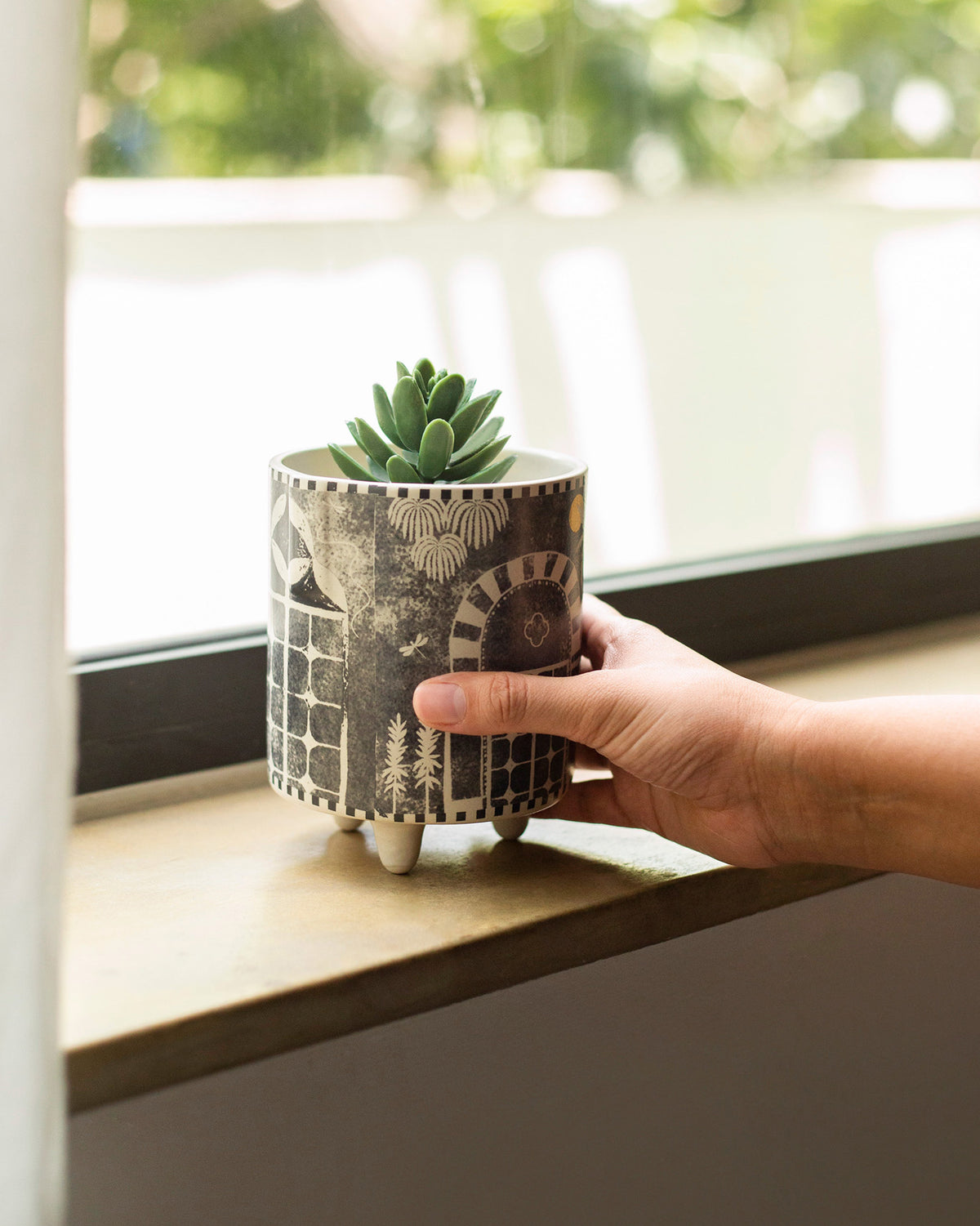 Hand holding a Mario planter with a succulent and arched motif.