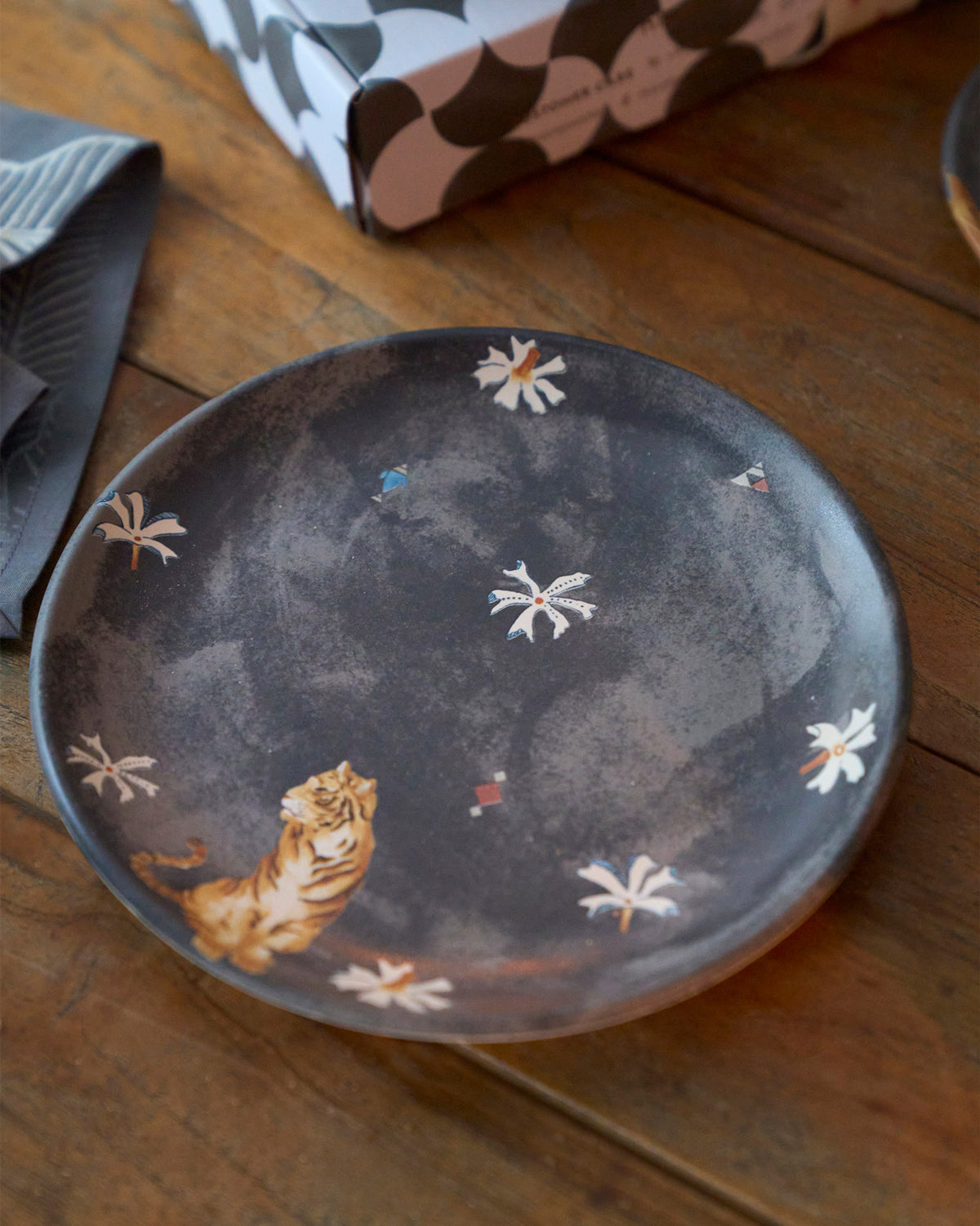 Charcoal Nadi quarter plate with a sitting orange tiger and white flower accents.