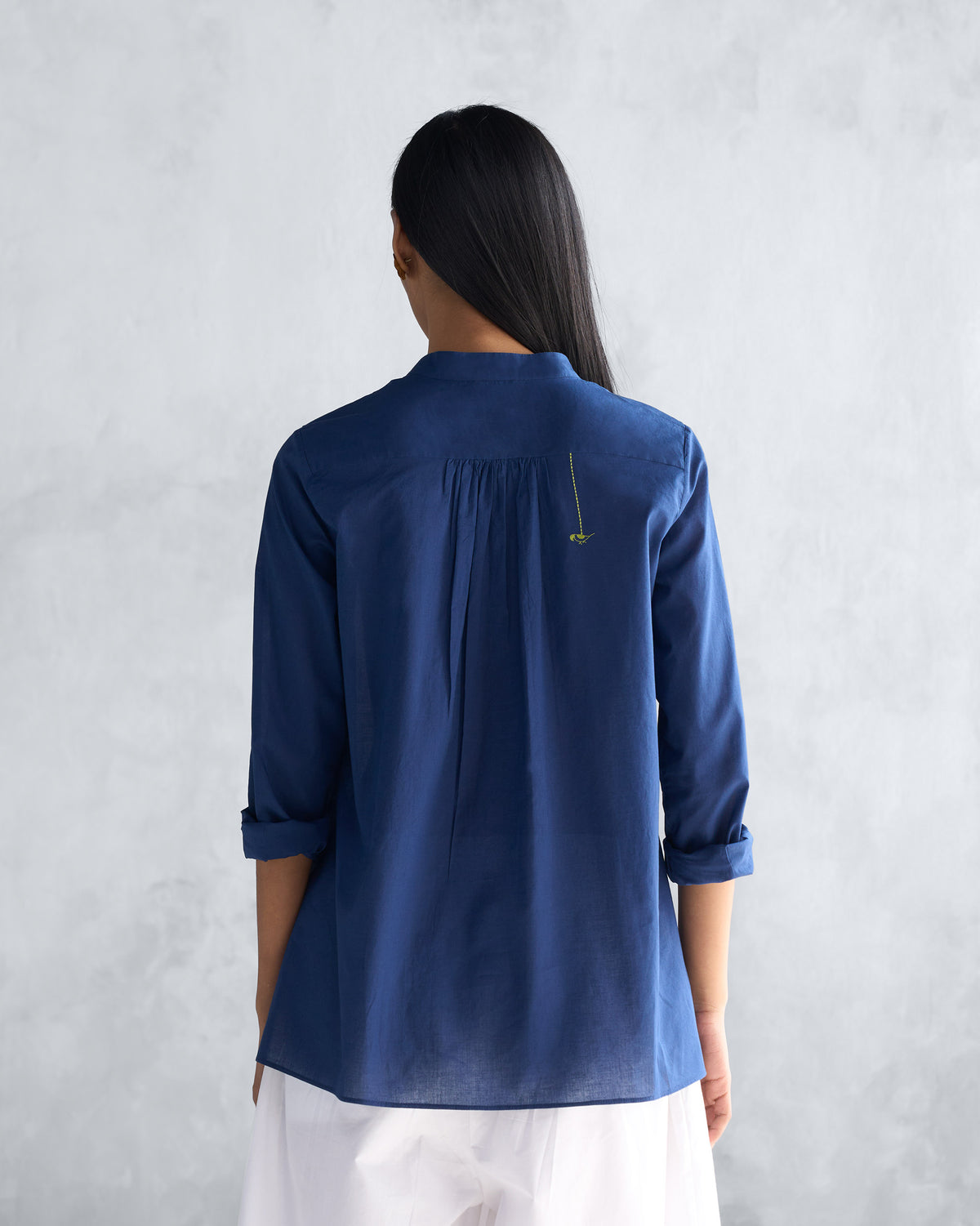 Back of a navy mandarin collar top with a small embroidered detail.