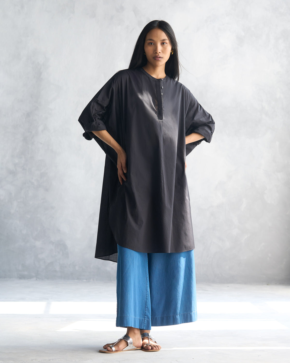 Person wearing a black Lazy Sunday tunic with rolled sleeves.