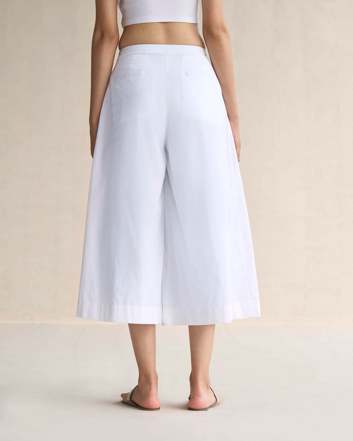 Back of white wide-leg culottes with two horizontal welt pockets.