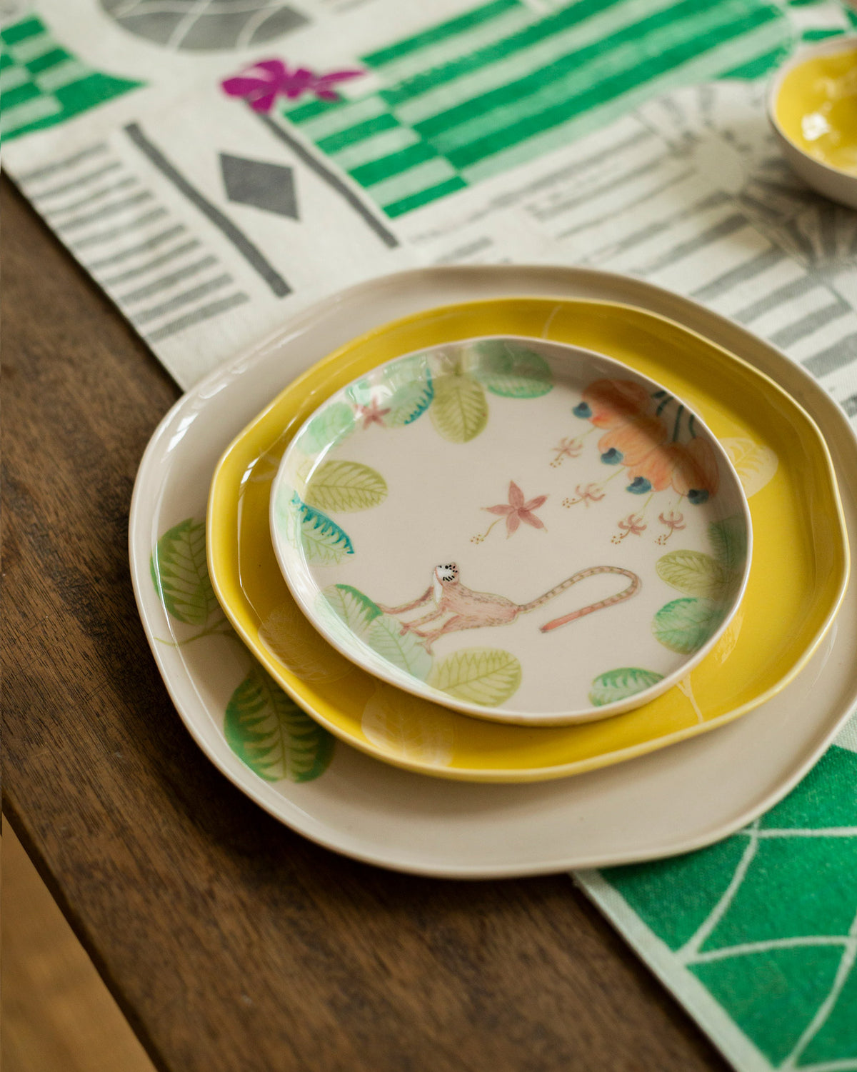 Mandovi dessert plate stacked on yellow and leaf-bordered plates.