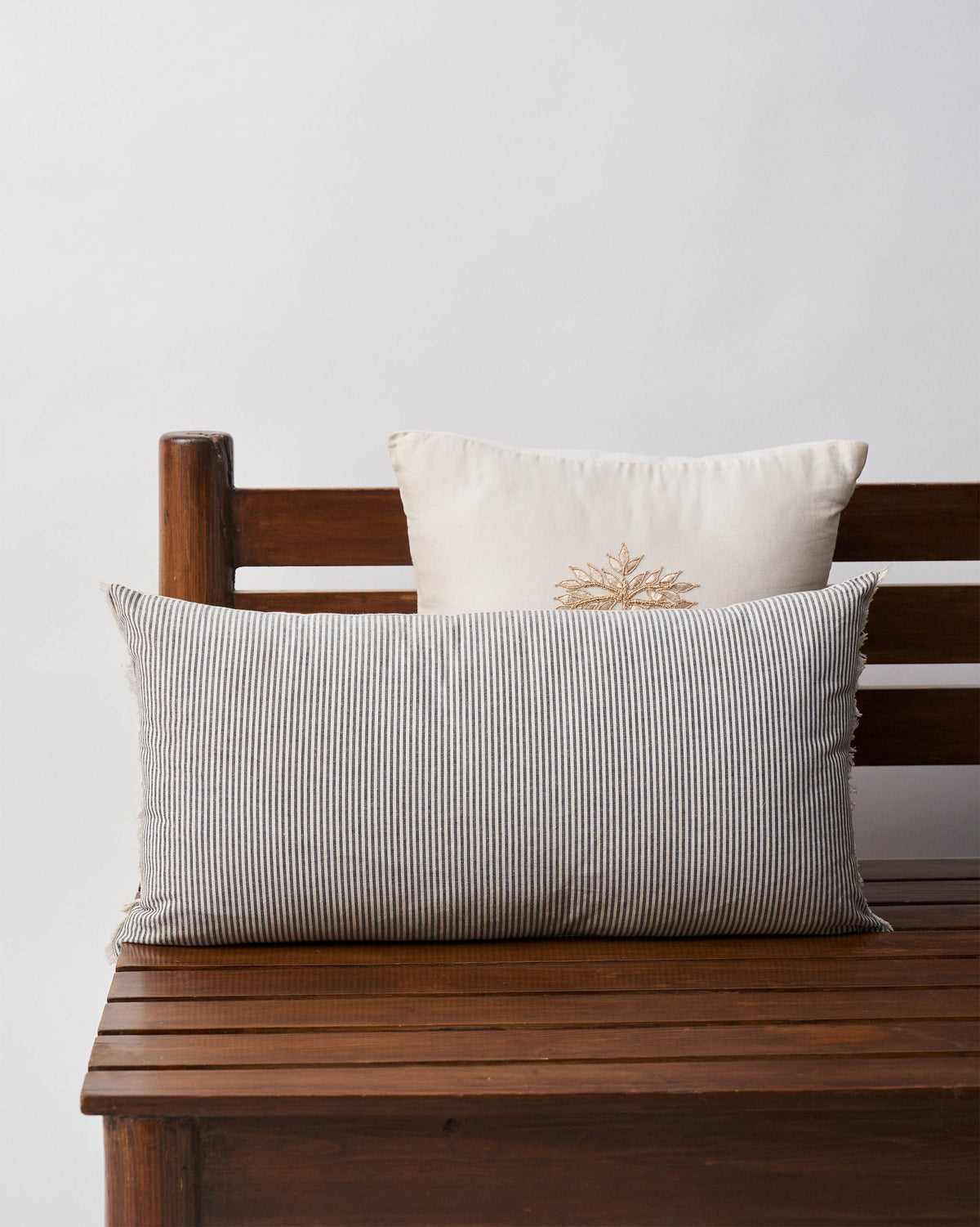 Black & White pillow cover with black and cream stripes on a wooden bench.