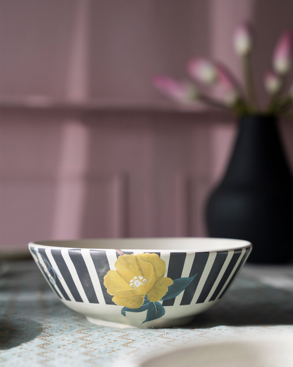 Side of a Myra curry bowl with charcoal stripes and a yellow flower.