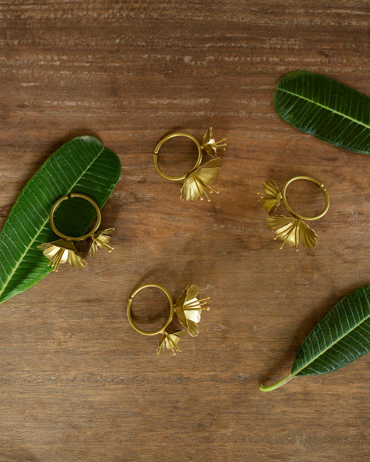 Set of four Kachnar Napkin Rings laid flat with gold flower motifs.