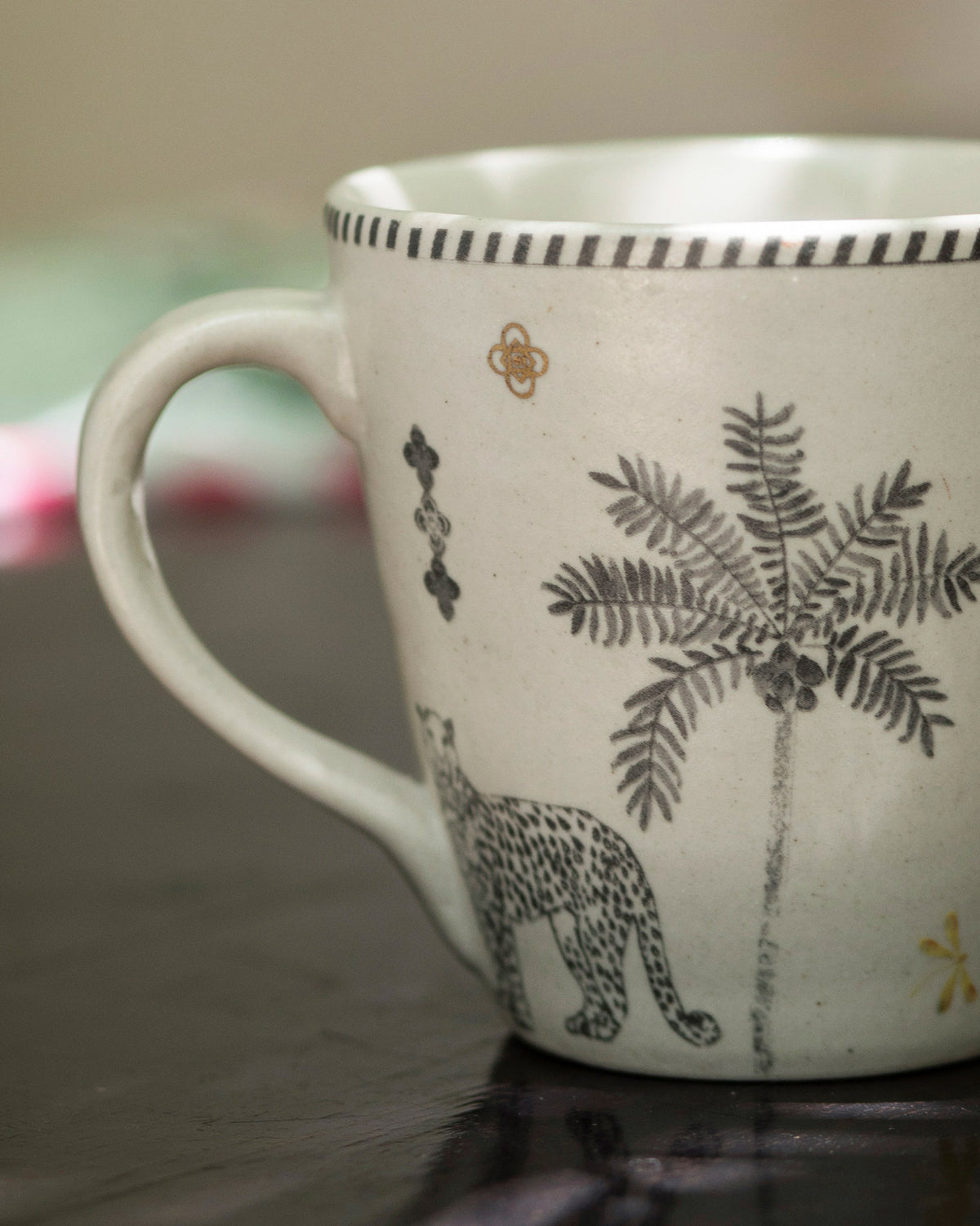 Close-up of Periyar Mug Ivory showing a leopard and palm tree motif.