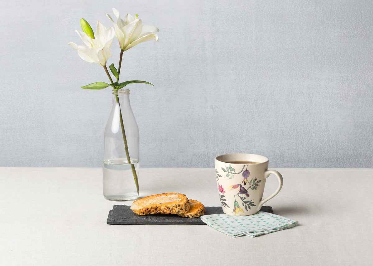 Nakano mug with birds and leafy branches set beside a biscuit.