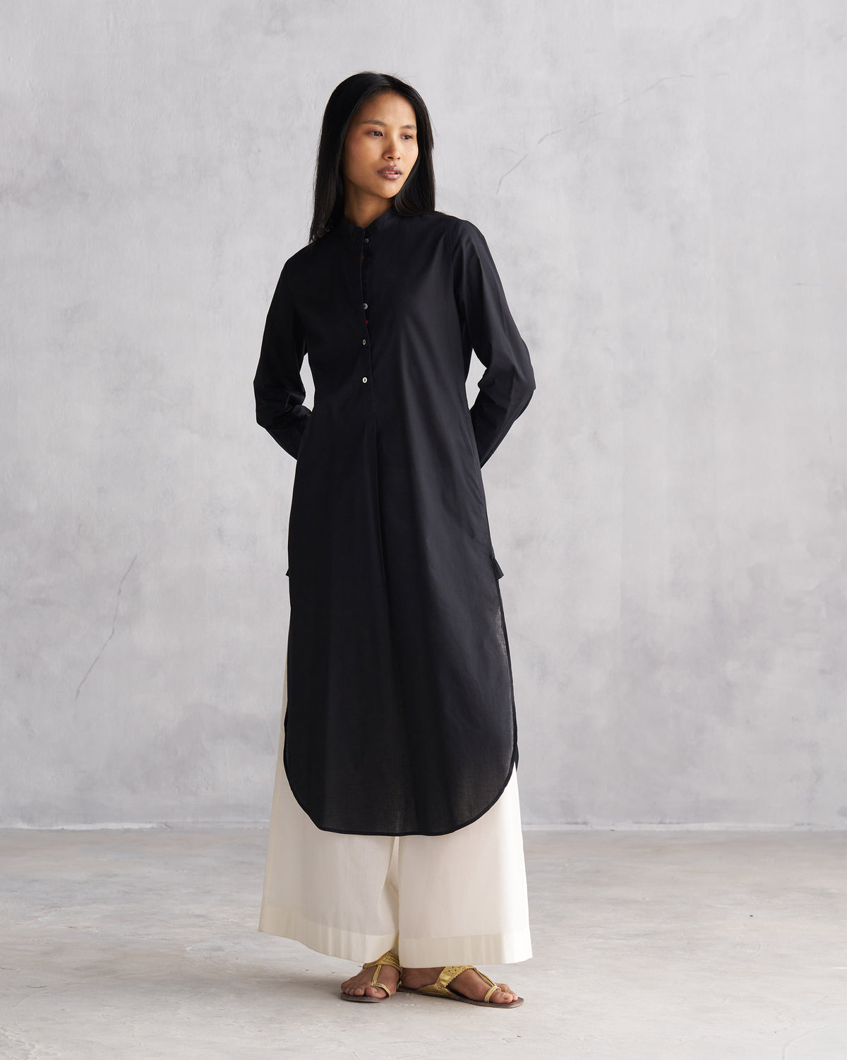 Person wearing a black long kurta with a curved hem and side slits.
