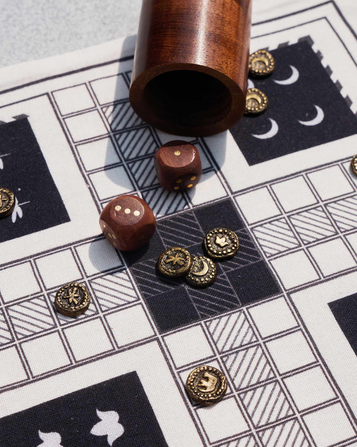 Wooden dice and brass tokens spilled across a Nico Ludo cloth board.