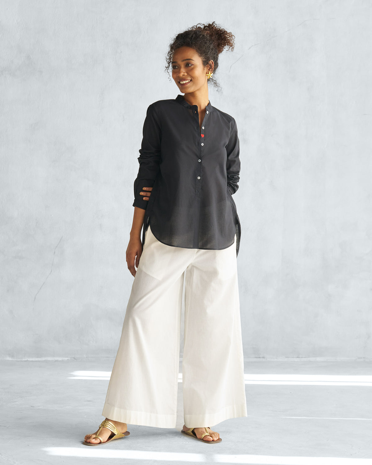 Three-quarter view of a black mandarin collar top showing hip-length hem.