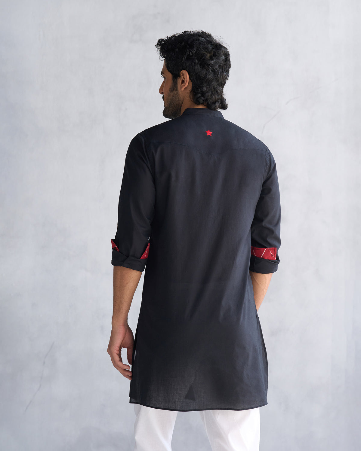 Back of a black Pondicherry kurta worn by a person, showing a red star.