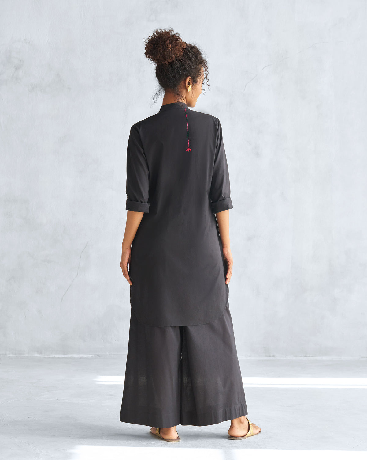 Back of a black mid-length kurta with embroidered detail.