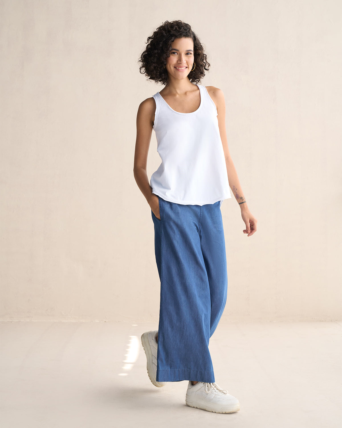 Person wearing a white Ukiyo racerback tank to the hip.