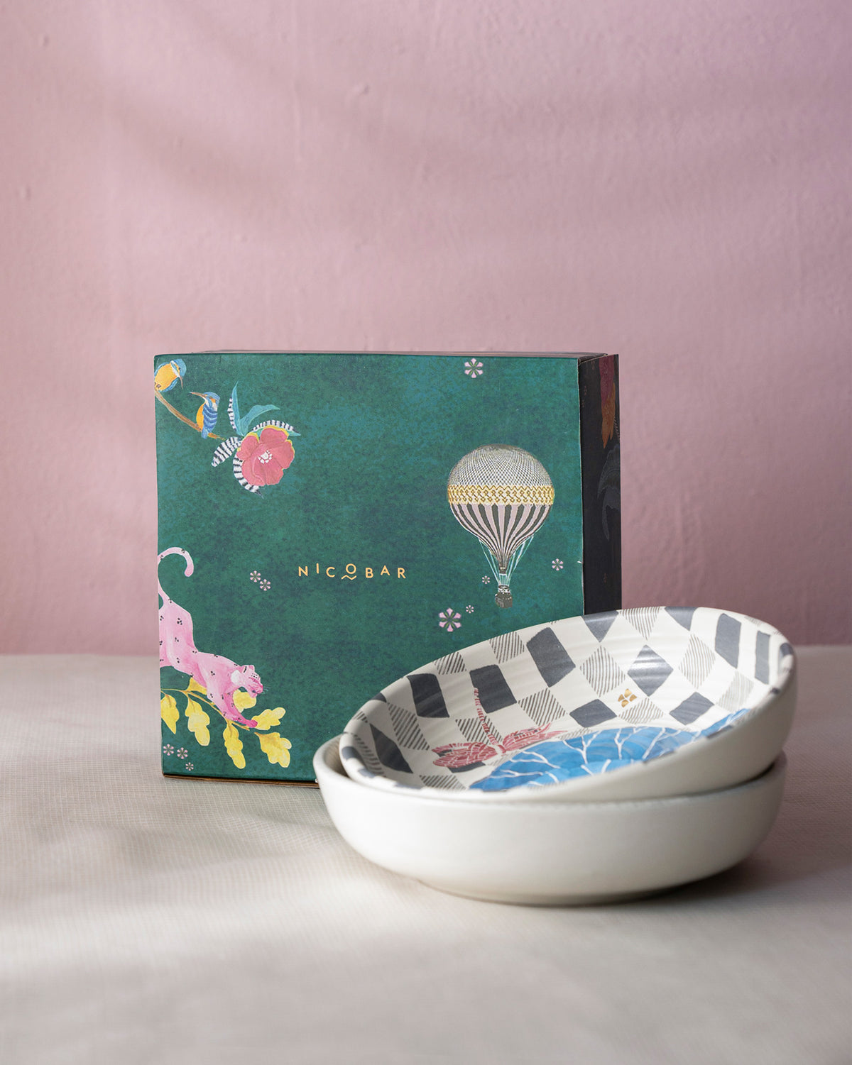 Pair of Nectar shallow bowls with botanical interiors beside a green illustrated gift box.