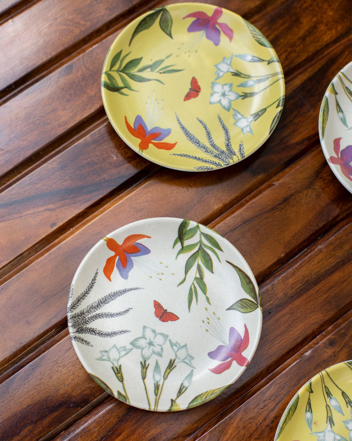 Overhead view of Botanical Tea Plates in yellow and cream with a red butterfly.