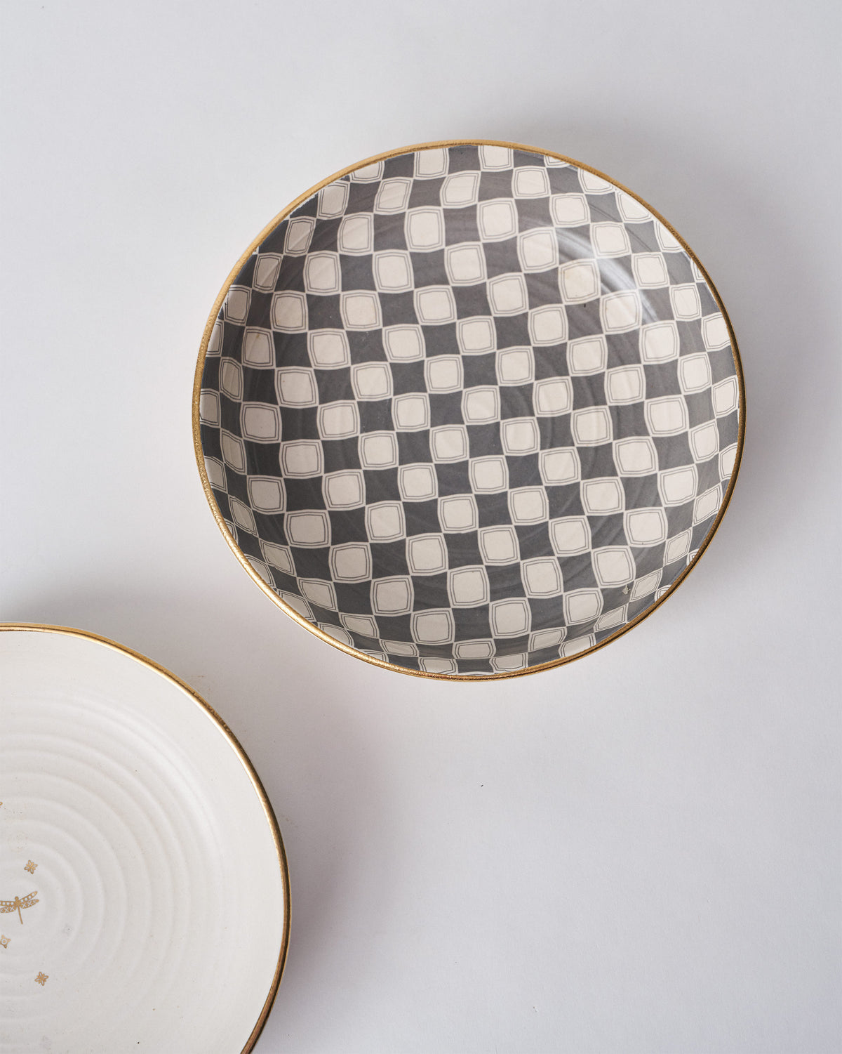 Fez Shallow Bowl with a grey checkered interior and a gold rim.