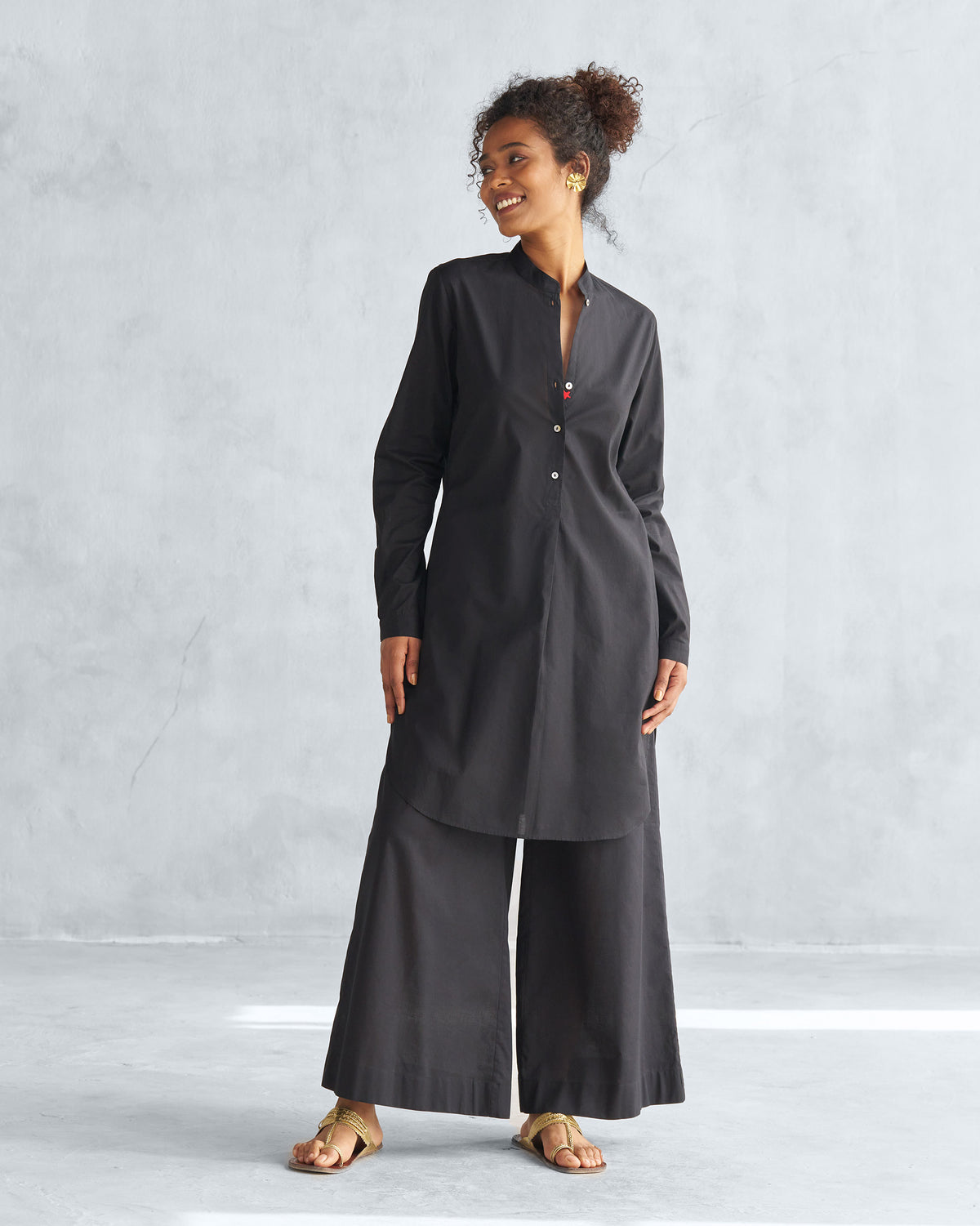 Person wearing a black mid-length kurta with a button placket.