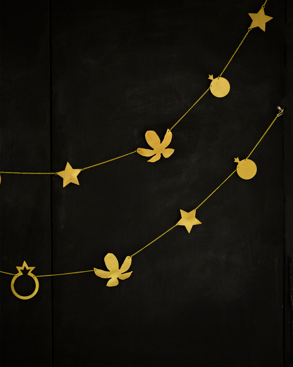 Close-up of Kachnaar Toran with gold star, flower and ring motifs on black.